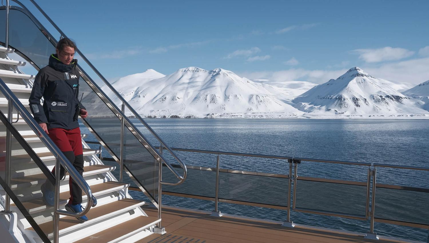 A guide aboard MS Bard walking down a flight of stairs