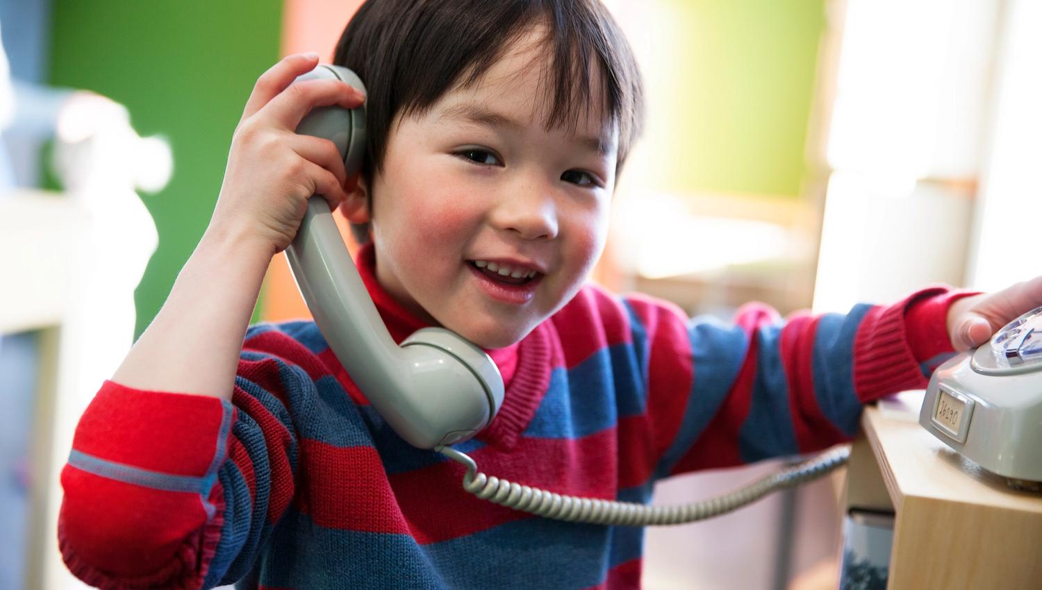 Smilande barn leikar med ein gammal telefon på Haugesenteret, ein del av den interaktive utstillinga.