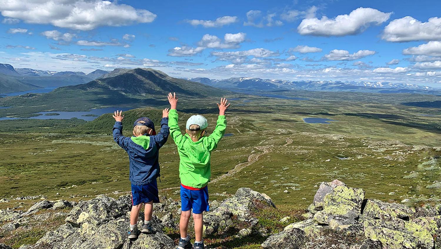 Children enjoy a great view over open mountain terrain with lakes and mountains.