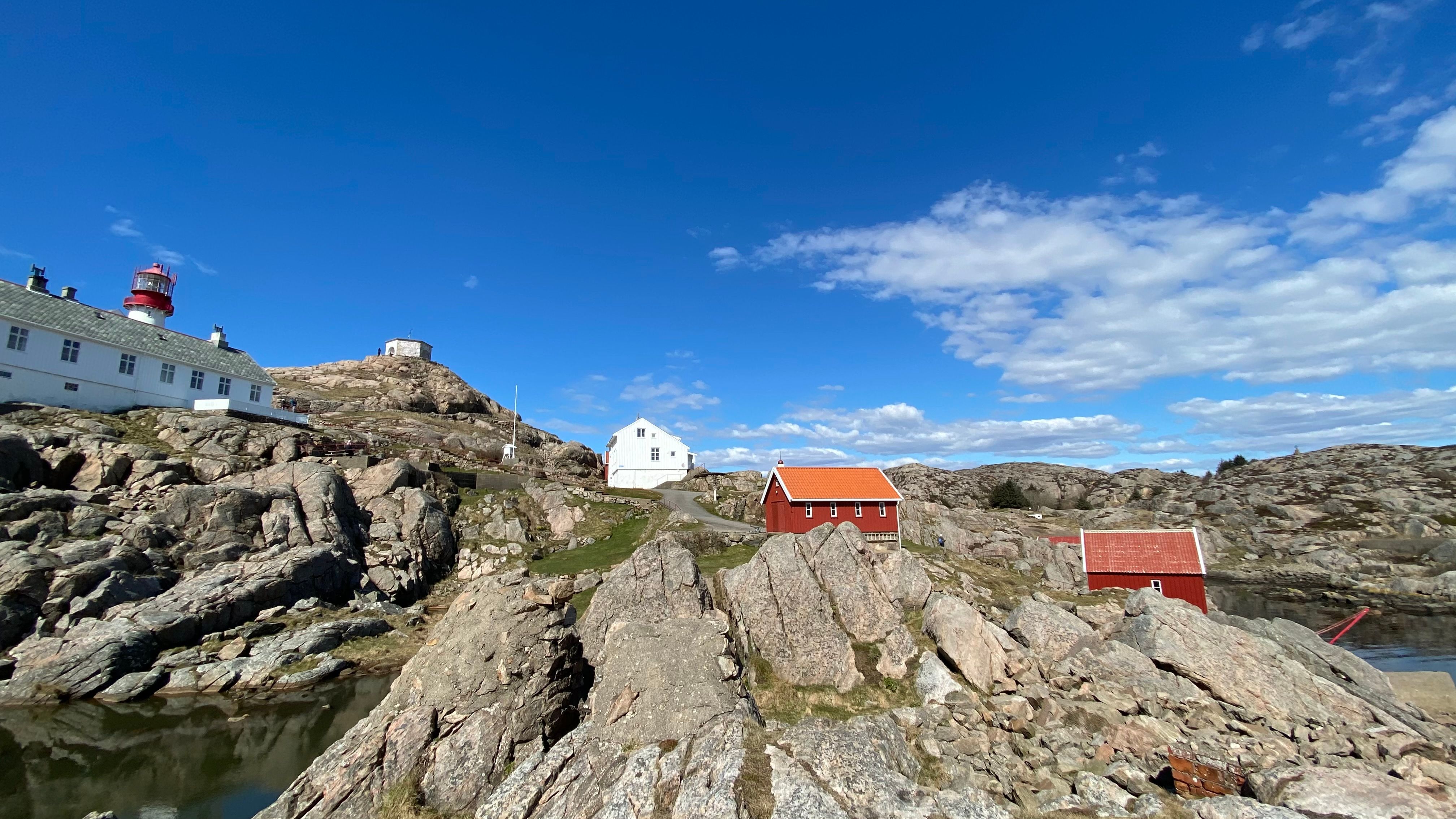 Utsikt fra homen opp mot fyrtårnet og andre bygninger i rødt og hvitt