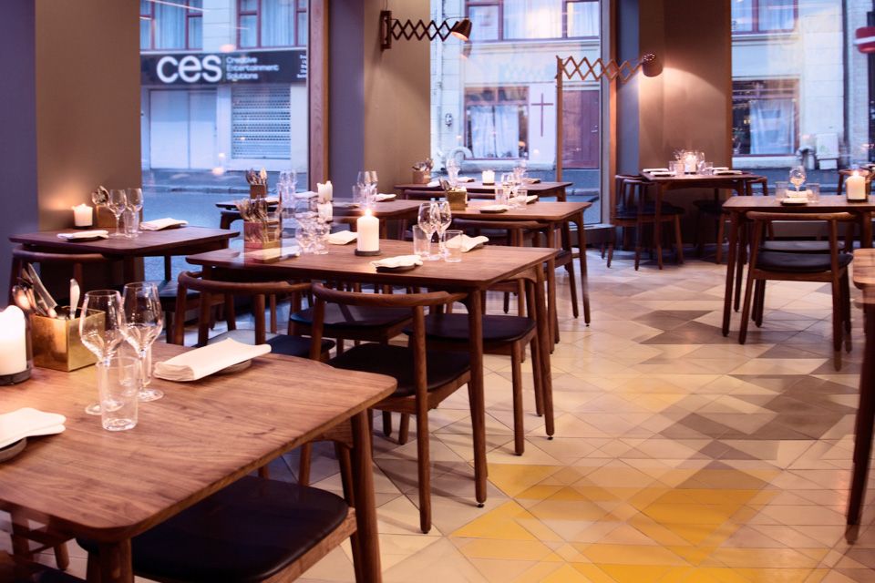 Restaurant interior of brown, wooden tables and chairs, with glasses and napkins on them. Scandinavian interior design.
