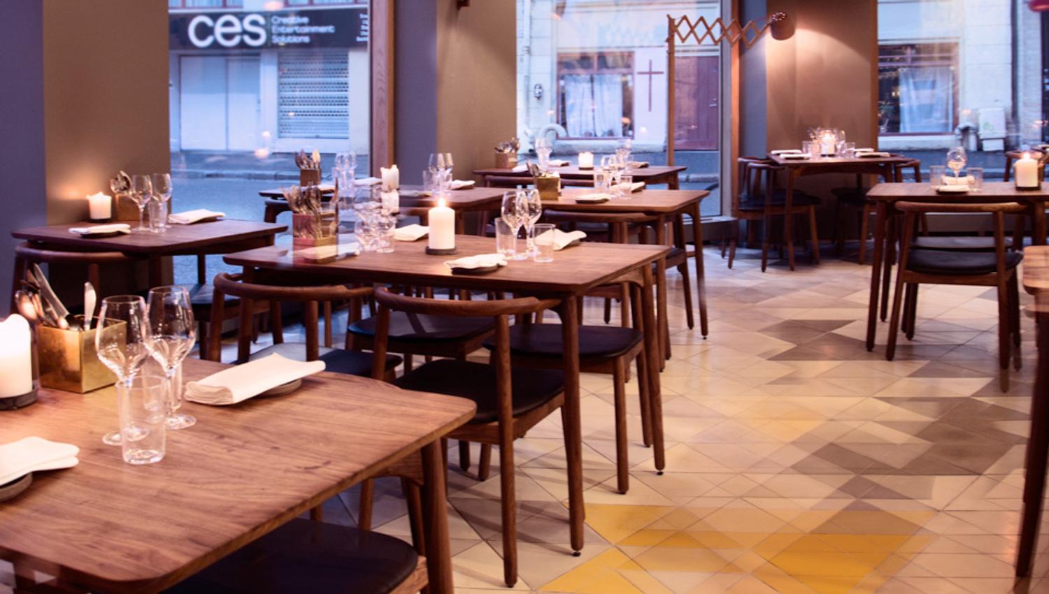 Restaurant interior of brown, wooden tables and chairs, with glasses and napkins on them. Scandinavian interior design.