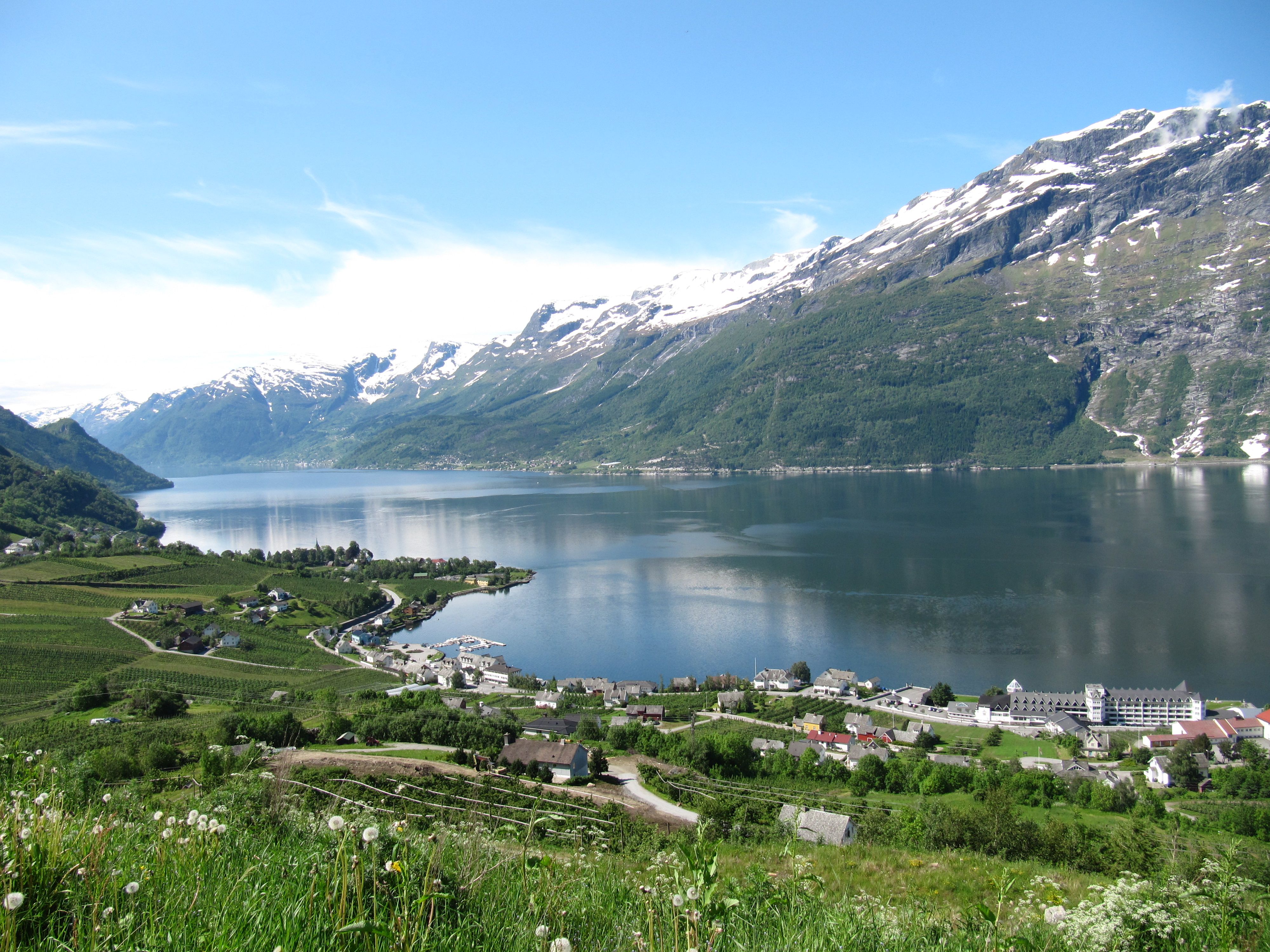 Utsikt over Sørfjorden og fruktbygdene i Hardanger, med snødekte fjell og glitrande vatn.