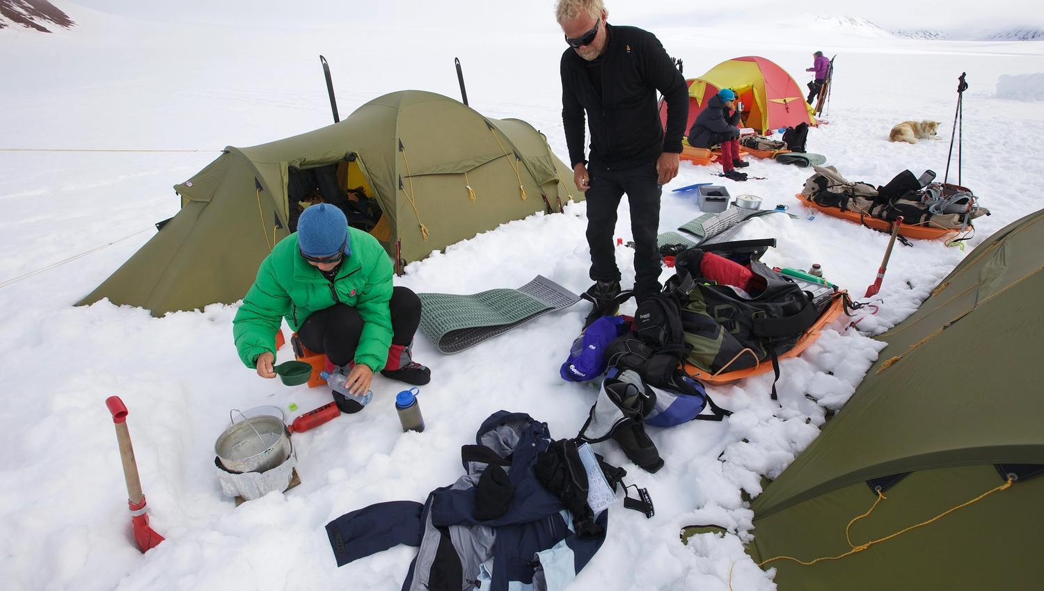 Two persons boiling water in a tent camp