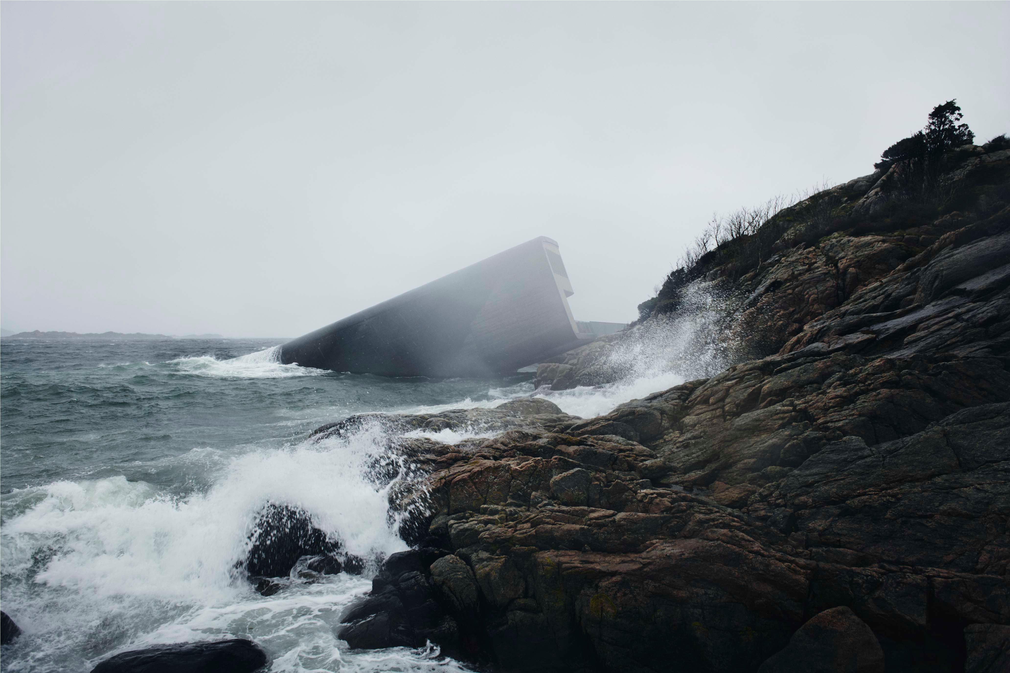 The restaurant in foggy weather with waves crashing against the rocky shore
