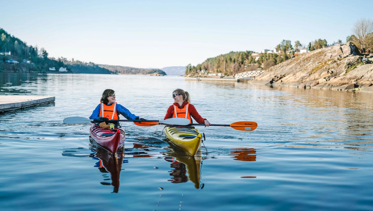 2 padlere i kajak, blått vann og svaberg
