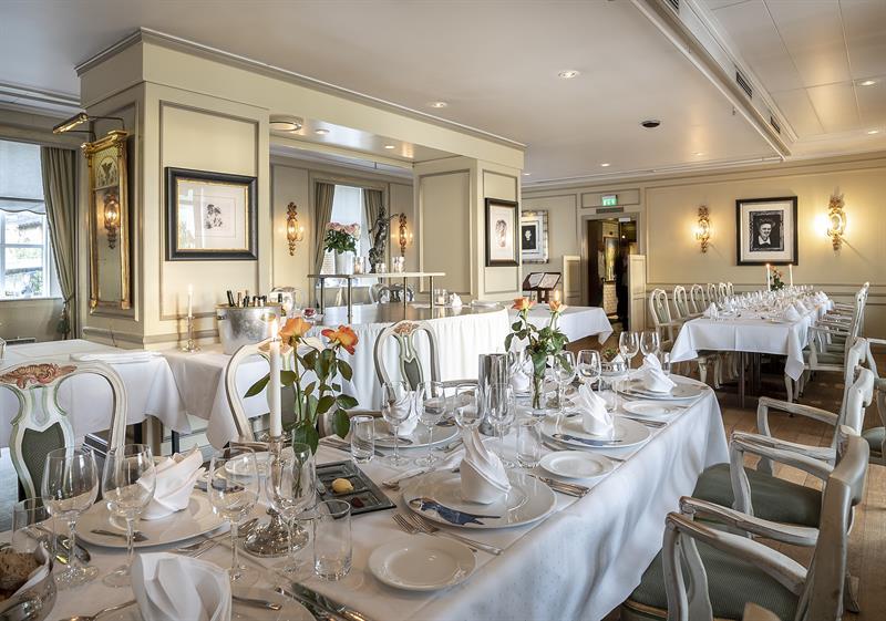 Elegant dining room with long tables, white tablecloths, and place settings for a dinner or event