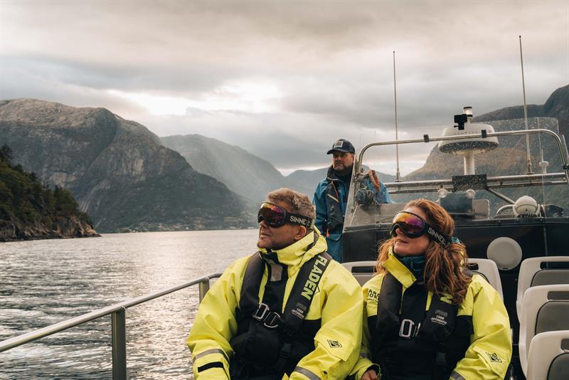 A couple and the captain onboard a rib boat, gazing towards the sky.