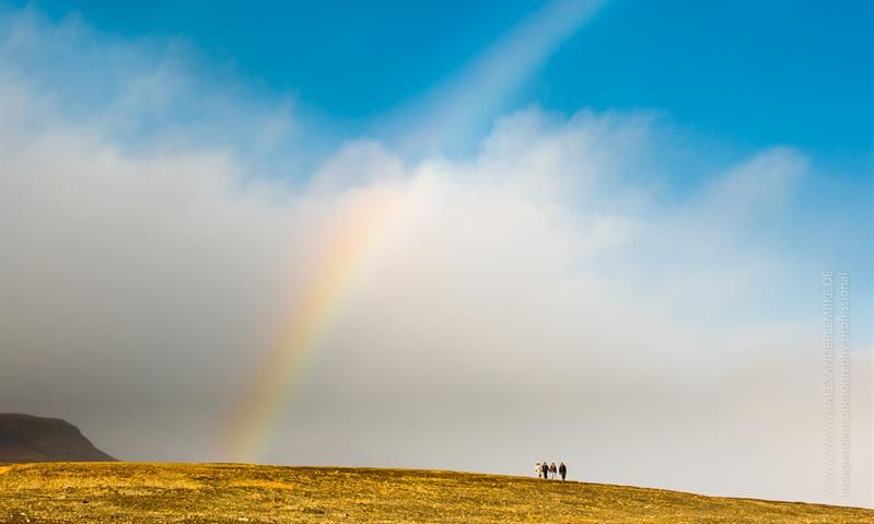 A group of people standing under the rainbow 