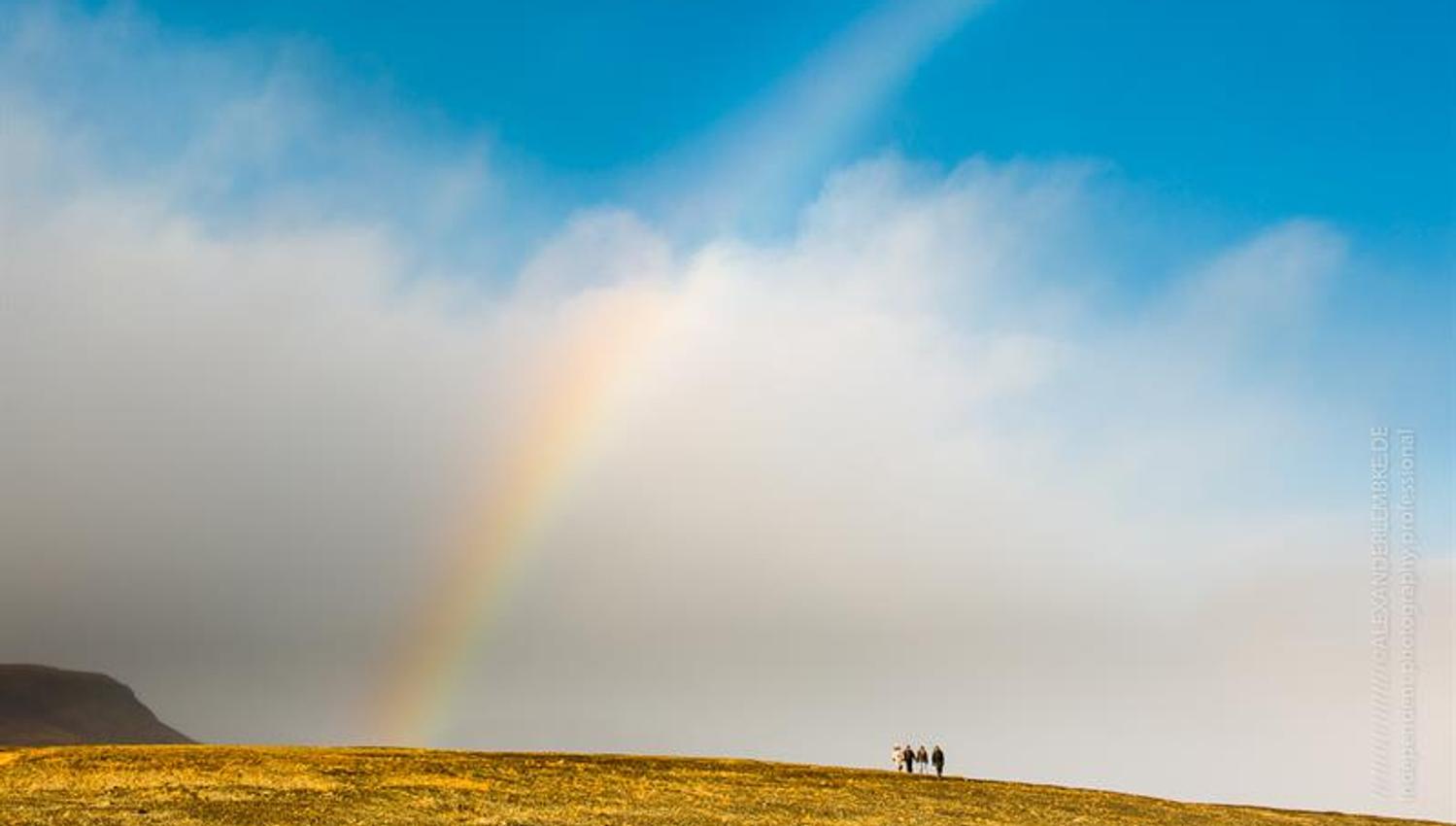 A group of people standing under the rainbow