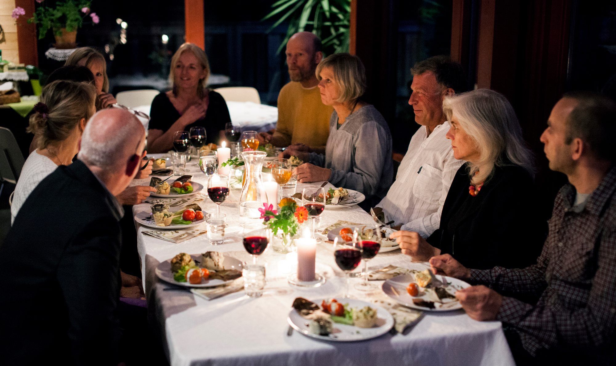 Adults eating food on a nicely set table in the evening