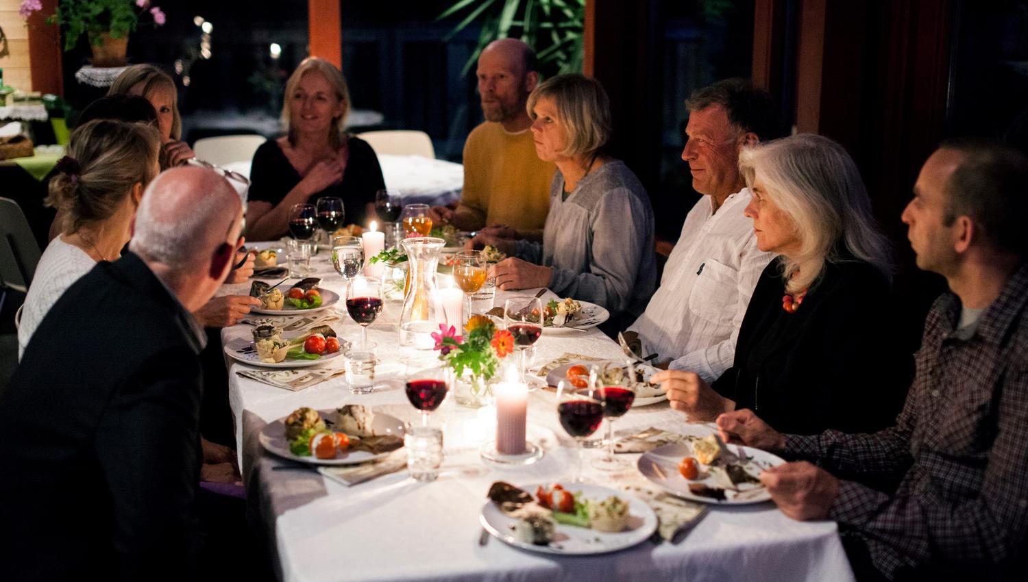 Adults eating food on a nicely set table in the evening