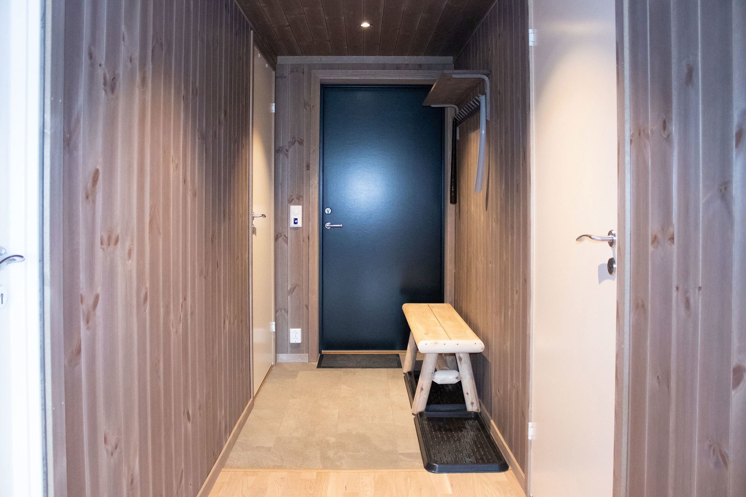 A hallway with a bench and a door.