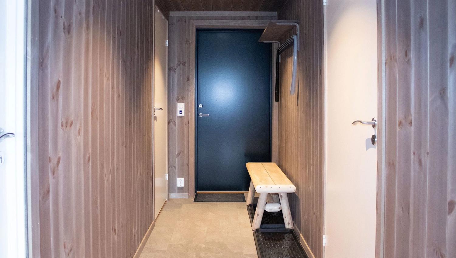 A hallway with a bench and a door.
