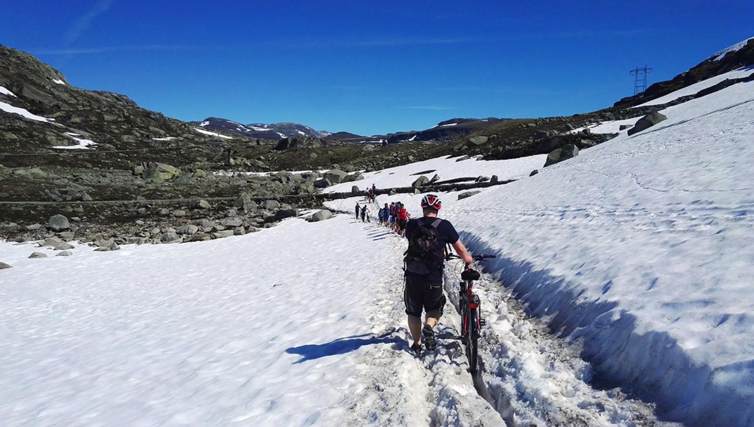 Syklistar triller syklane gjennom snøen på Rallarvegen tidleg i sesongen.