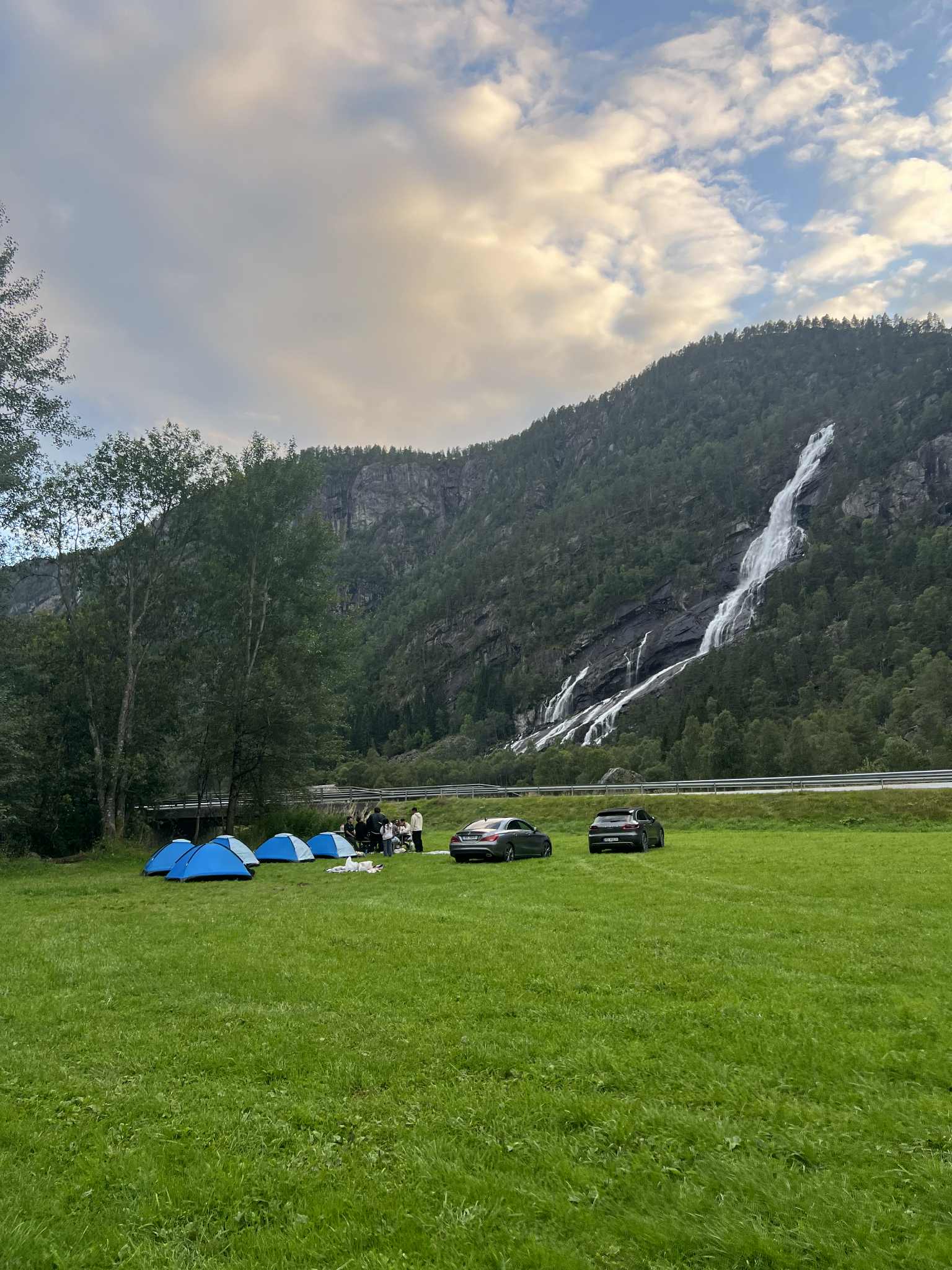 Telt og bilar på Hildal Camping med kveldssol over foss og fjell.