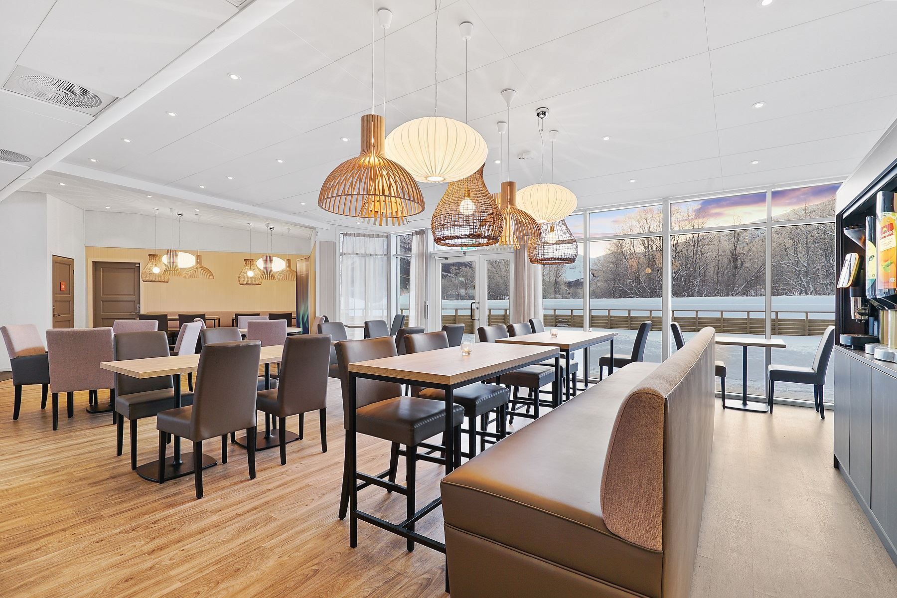 Modern dining room with large windows, wooden furniture, and natural light