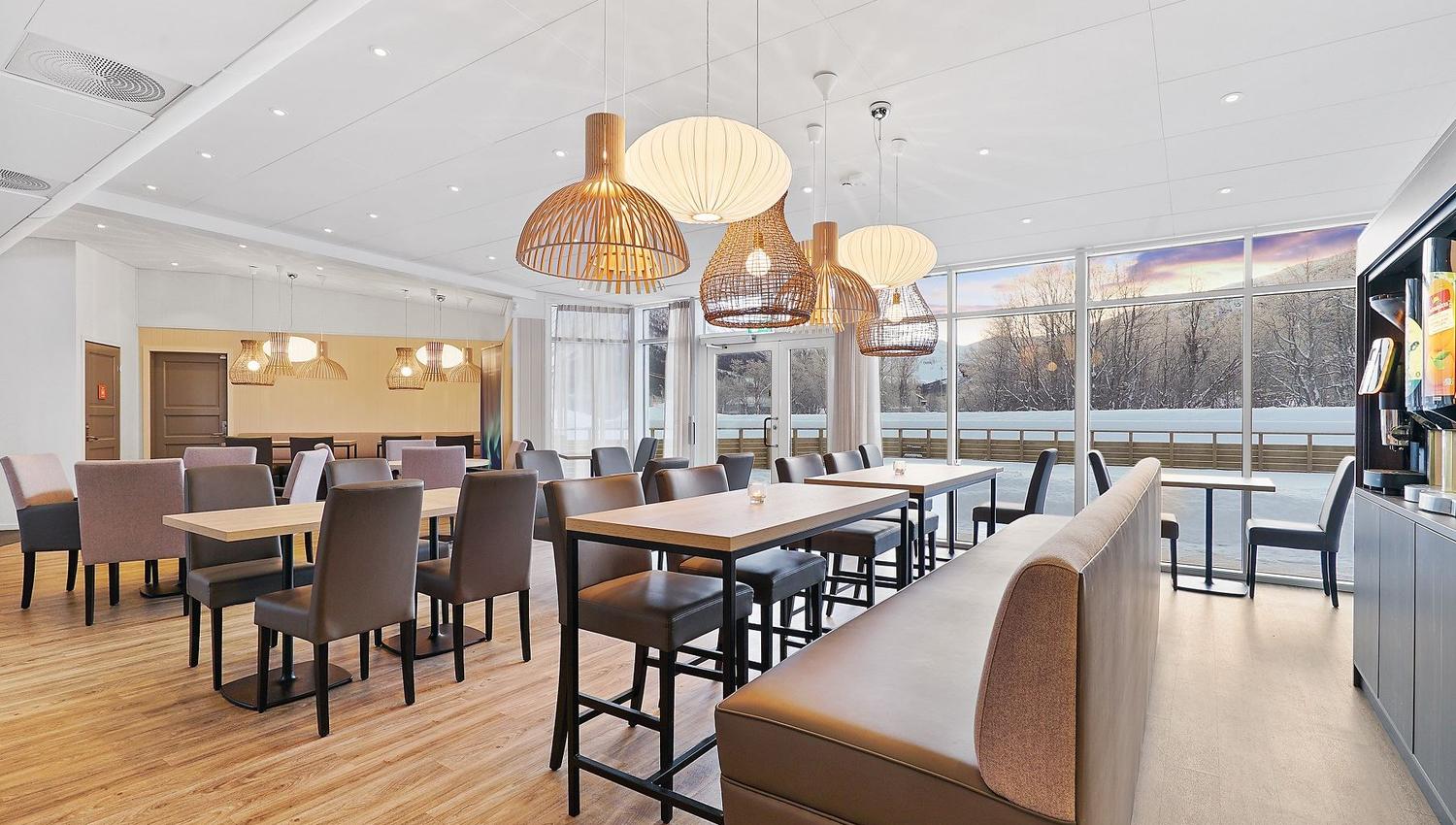 Modern dining room with large windows, wooden furniture, and natural light