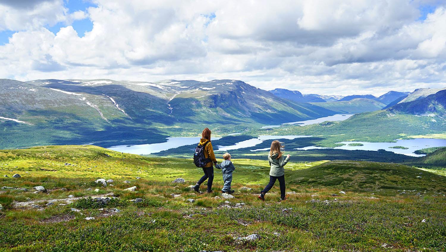 Family hiking in open mountain landscape with lakes and peaks