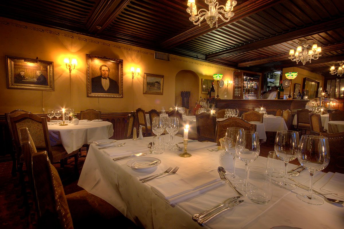 Interiør med dekkede bord i hvite duker, gamle malerier på de gule veggene.