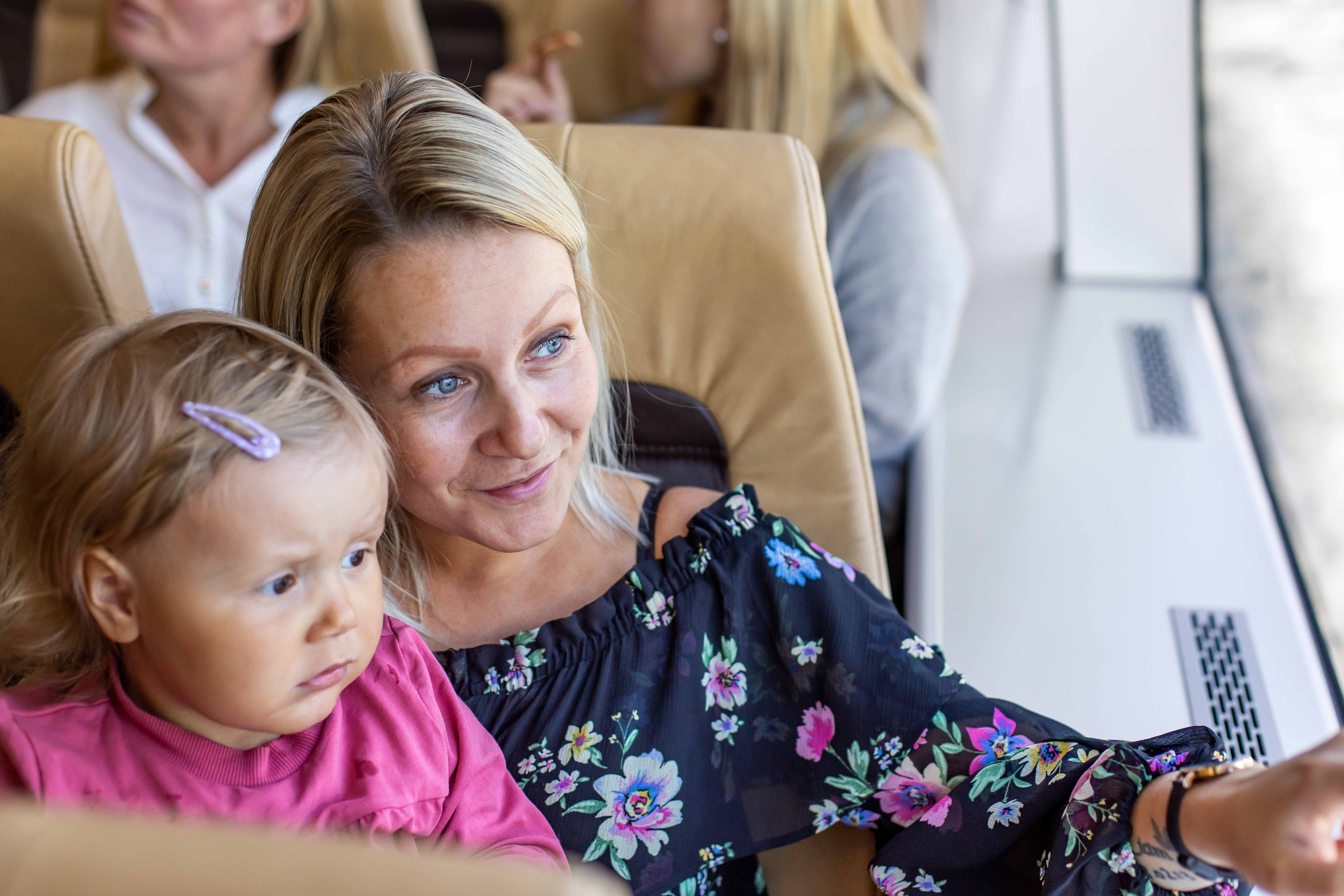 Mor og dotter sit inne og peikar ut på Hardangerfjorden frå båt.