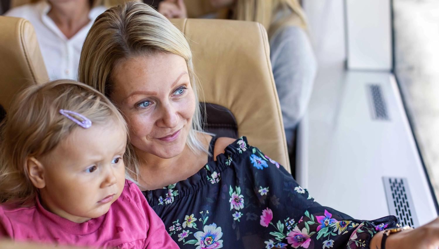 Mor og dotter sit inne og peikar ut på Hardangerfjorden frå båt.