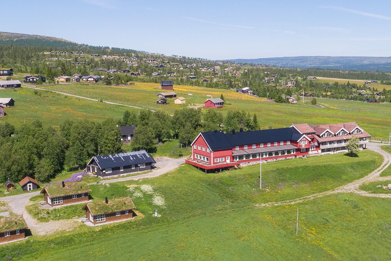 Done footage of a red wooden hotel in a green summer meadow landscape