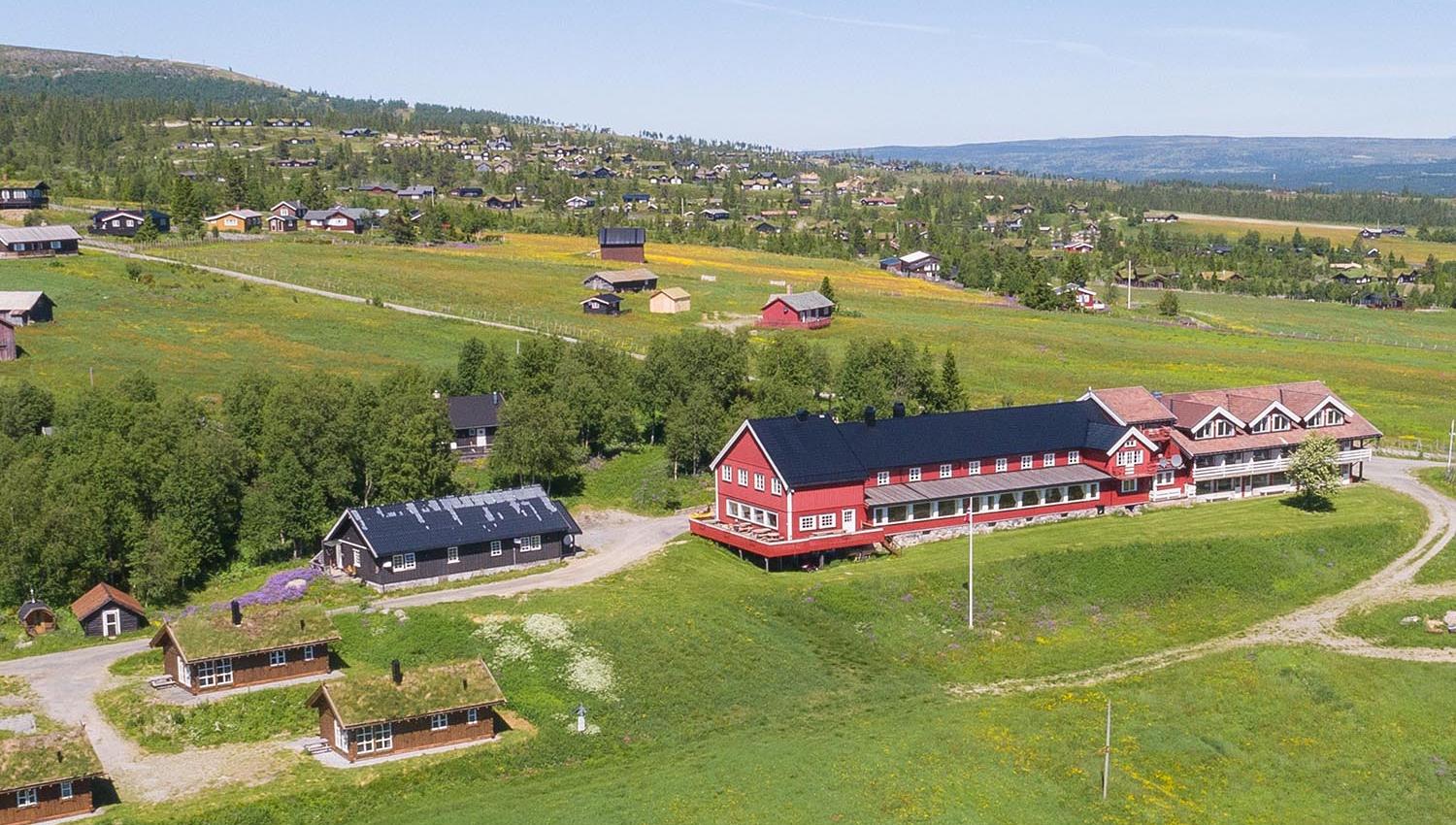 Done footage of a red wooden hotel in a green summer meadow landscape