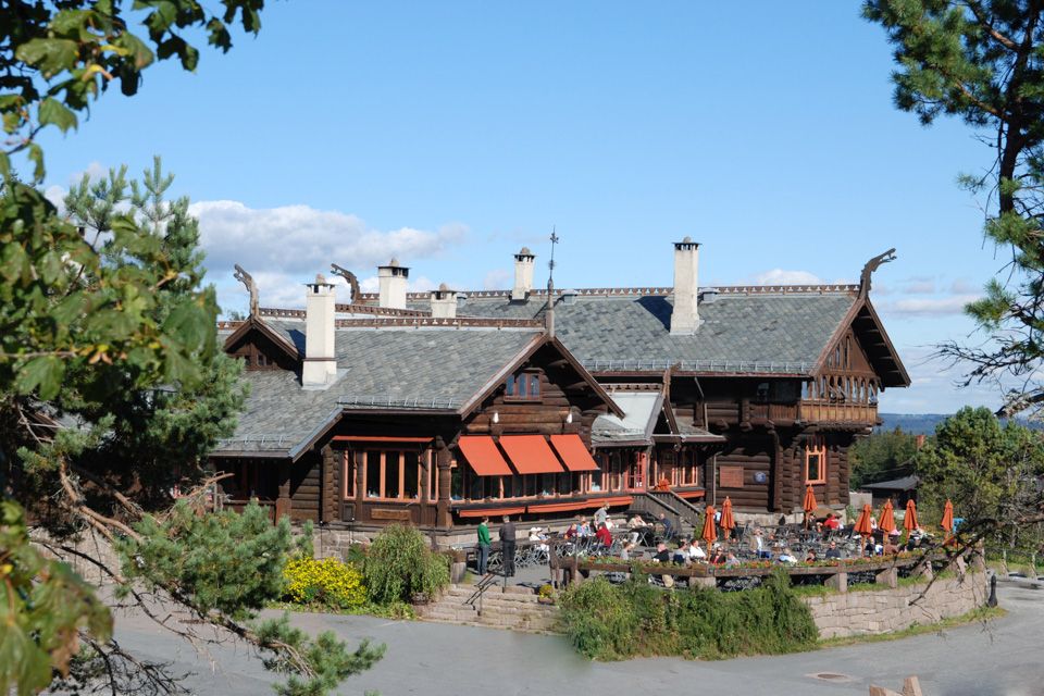 Exterior of Frognerseter. Wooden house with outdoor seating.