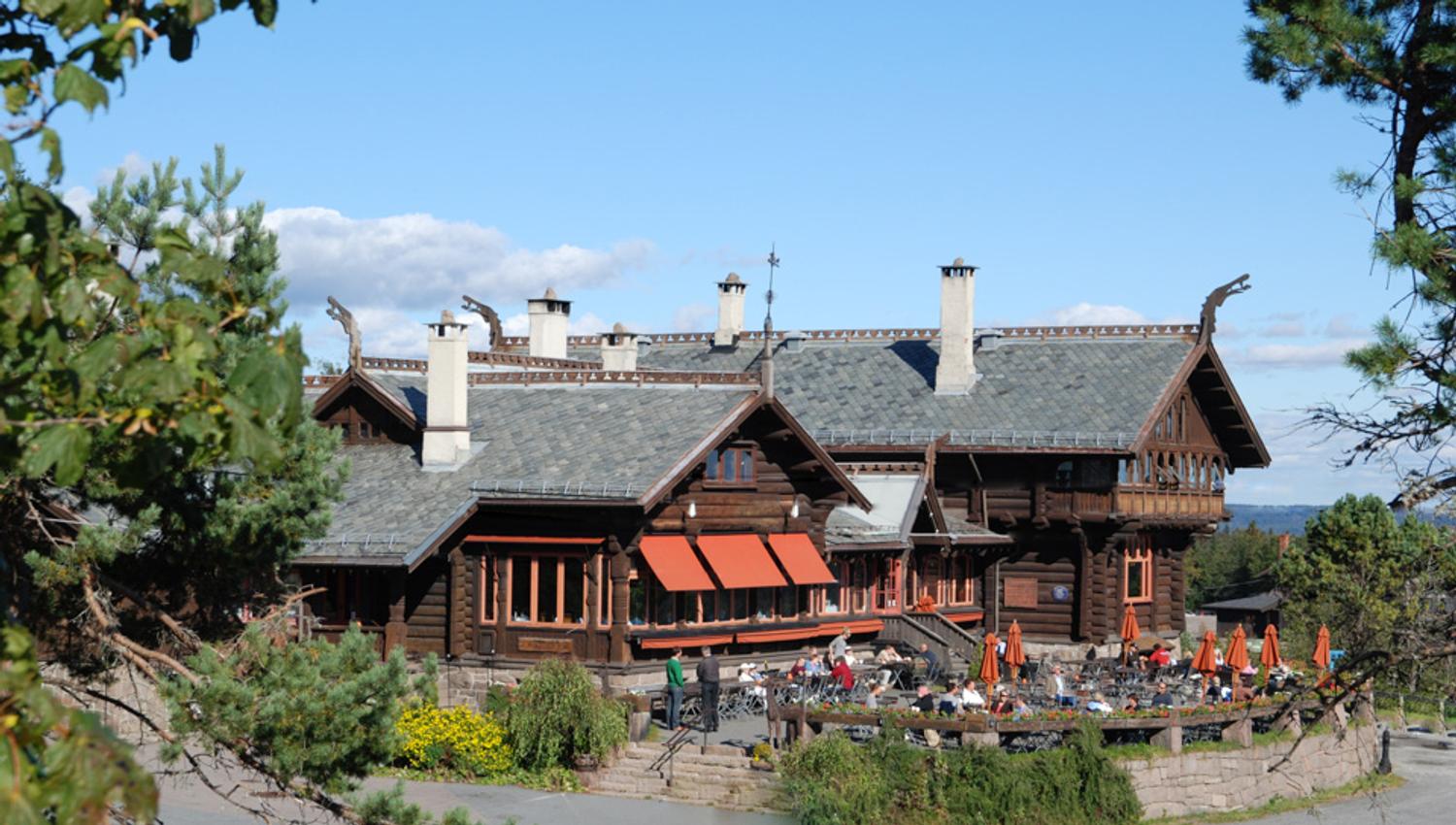 Exterior of Frognerseter. Wooden house with outdoor seating.