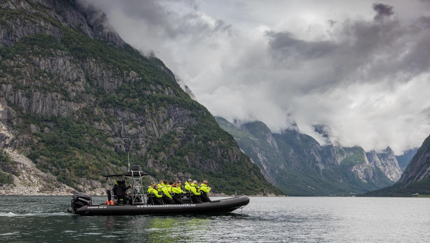 En ribbåt på fjorden, fylt med passasjerer.