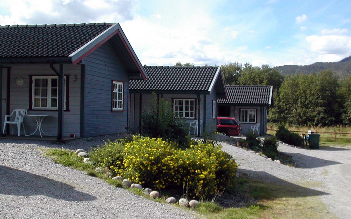 Tre grå hytter ved Langnes camping.