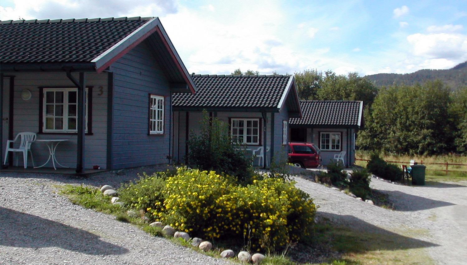 Tre grå hytter ved Langnes camping.