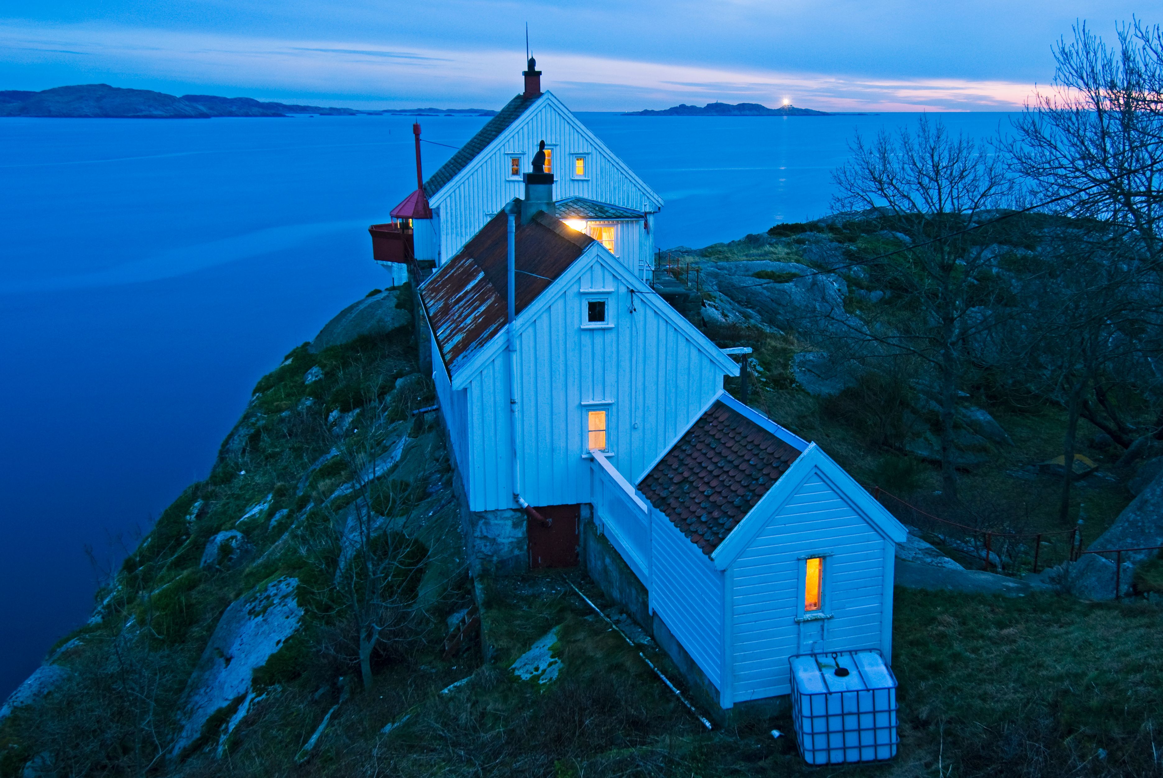 The house at Hatholmen Lighthouse, with the lighthouse behind it and a view out to the sea.