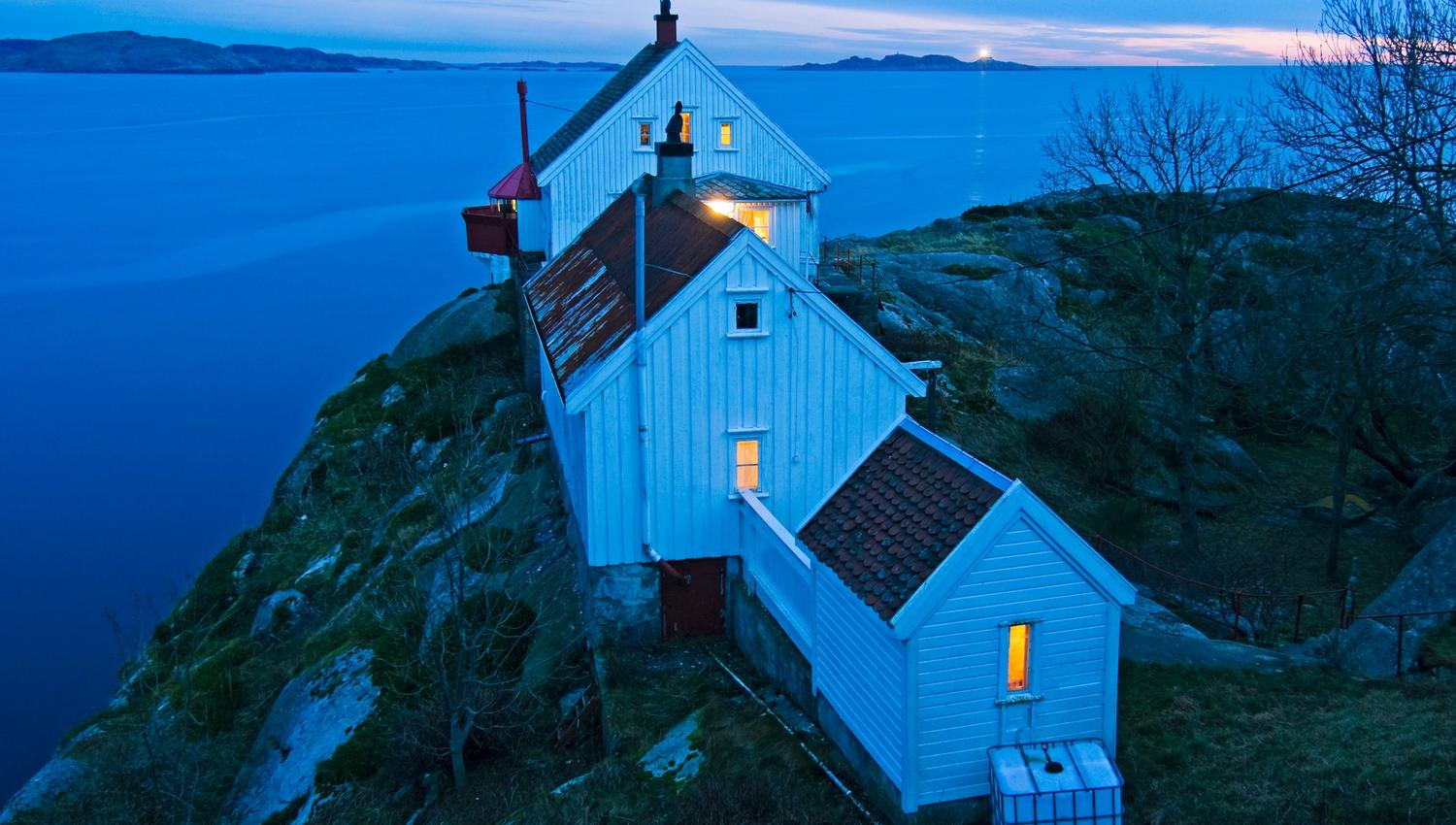 The house at Hatholmen Lighthouse, with the lighthouse behind it and a view out to the sea.