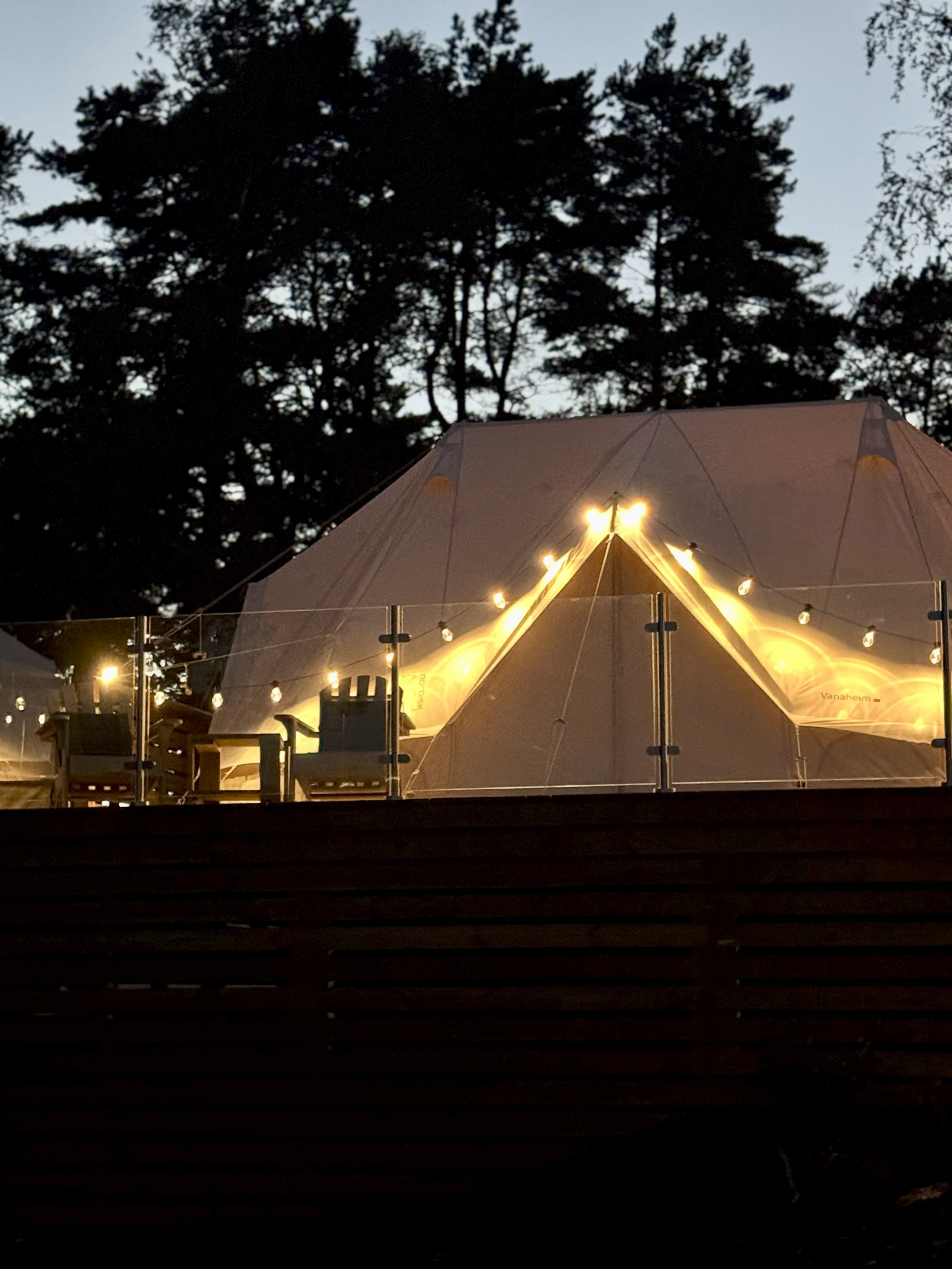 Fasade på glampingtelt i mørket, med lys som omkranser åpningen