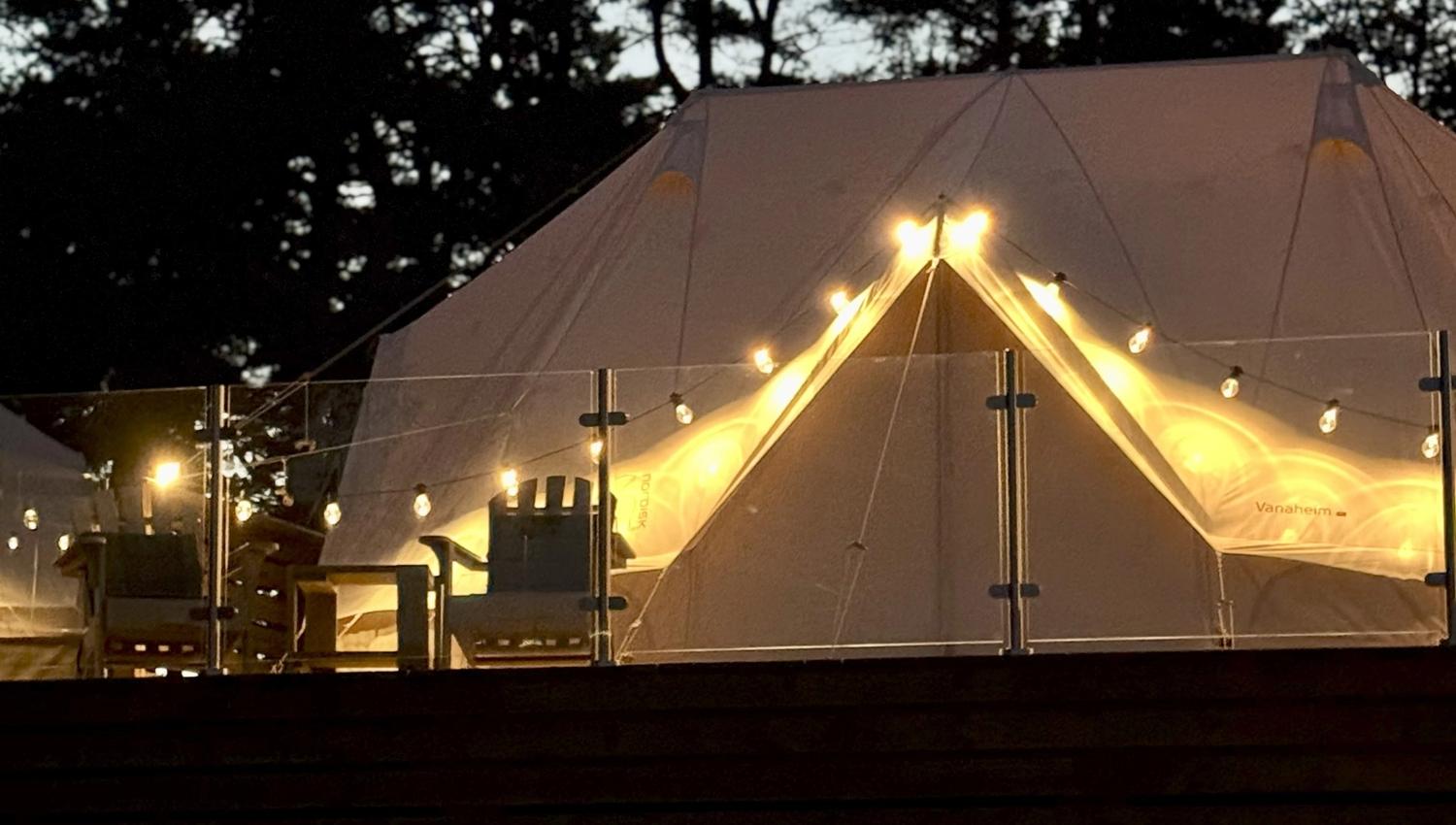 Fasade på glampingtelt i mørket, med lys som omkranser åpningen