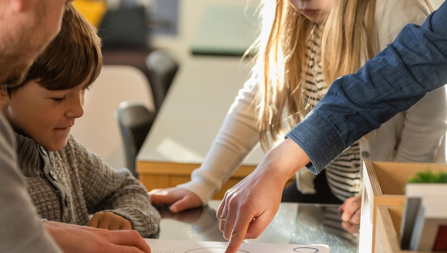 Familie samarbeider om ei oppgåve på Haugesenteret, der dei lærer om typografi og tekst frå Hauge sine dikt.