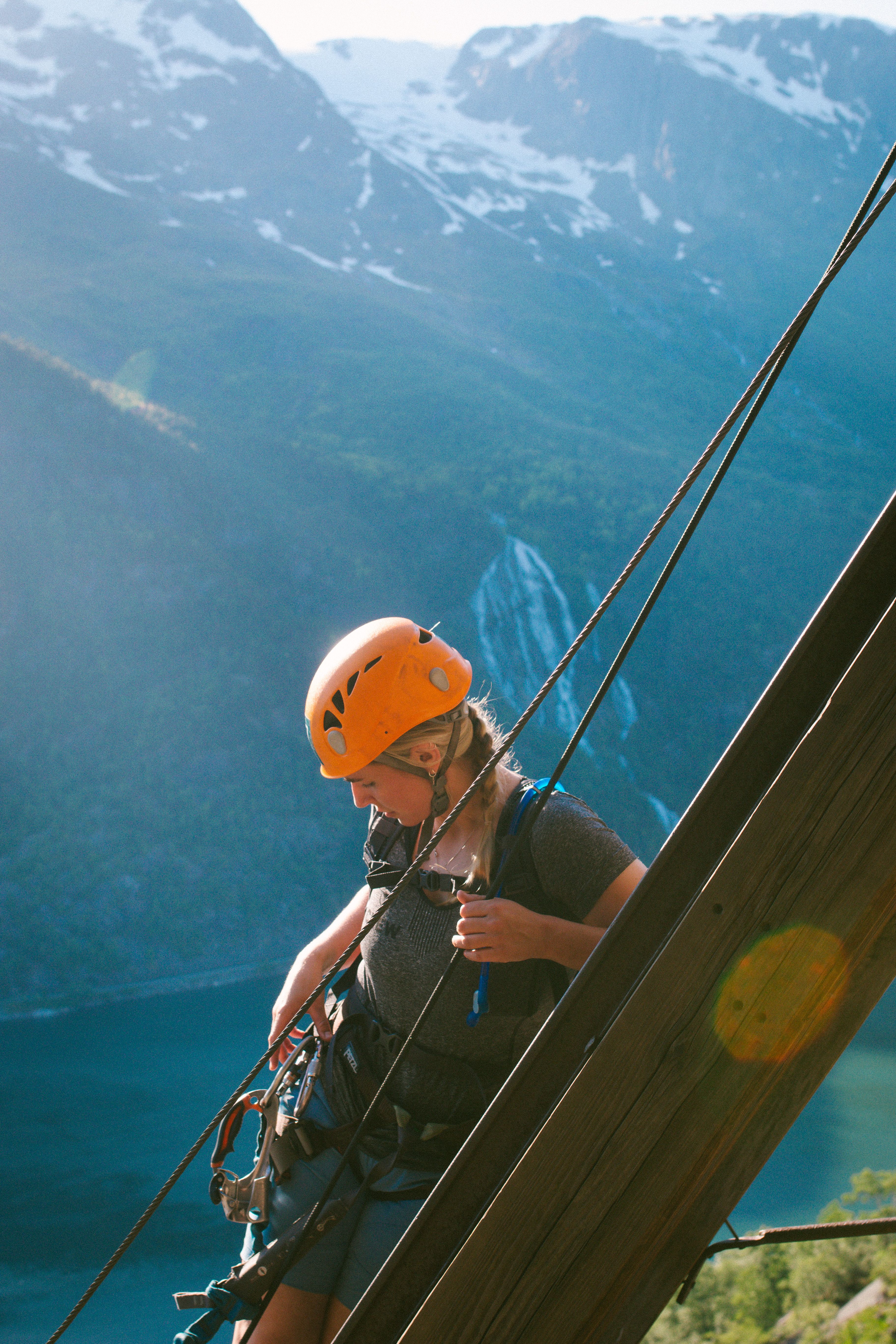 Klatrar sikra i vaier med foss og fjell i bakgrunnen i Tyssedal.