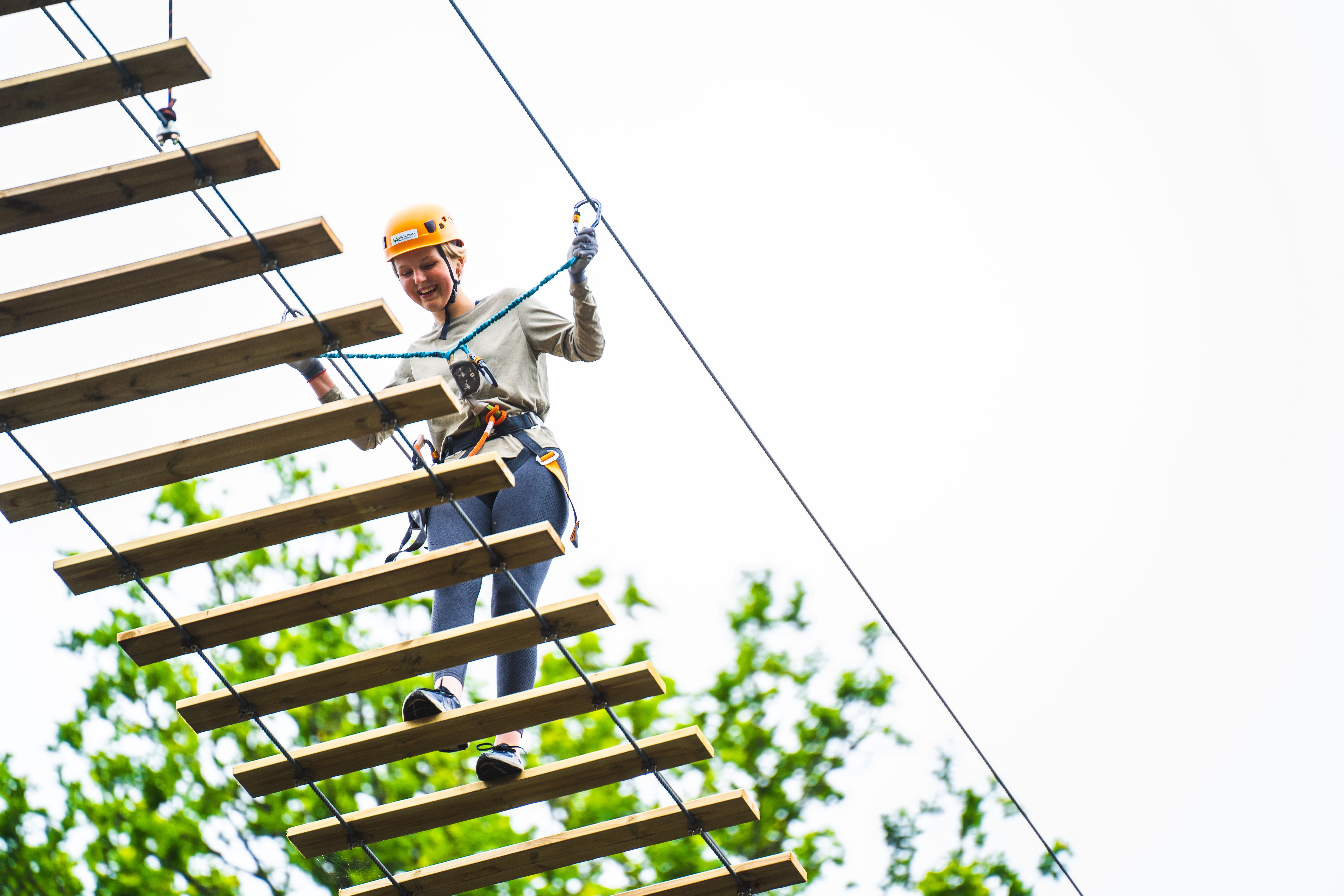 Jente som går over hengebroa over kanalen, i Via ferrata Haldenkanalen