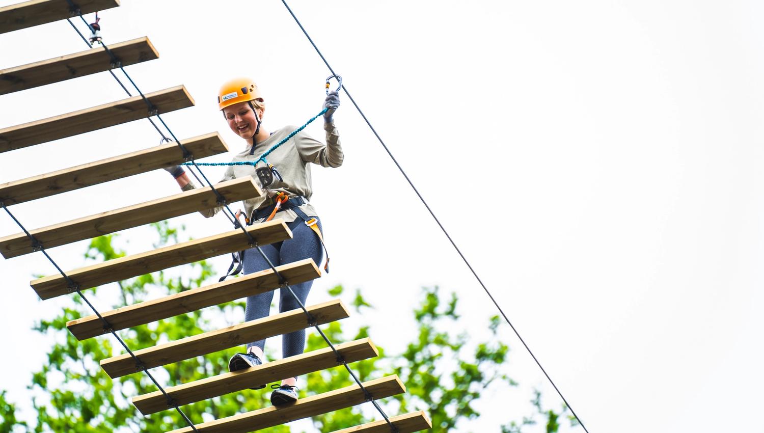 Jente som går over hengebroa over kanalen, i Via ferrata Haldenkanalen