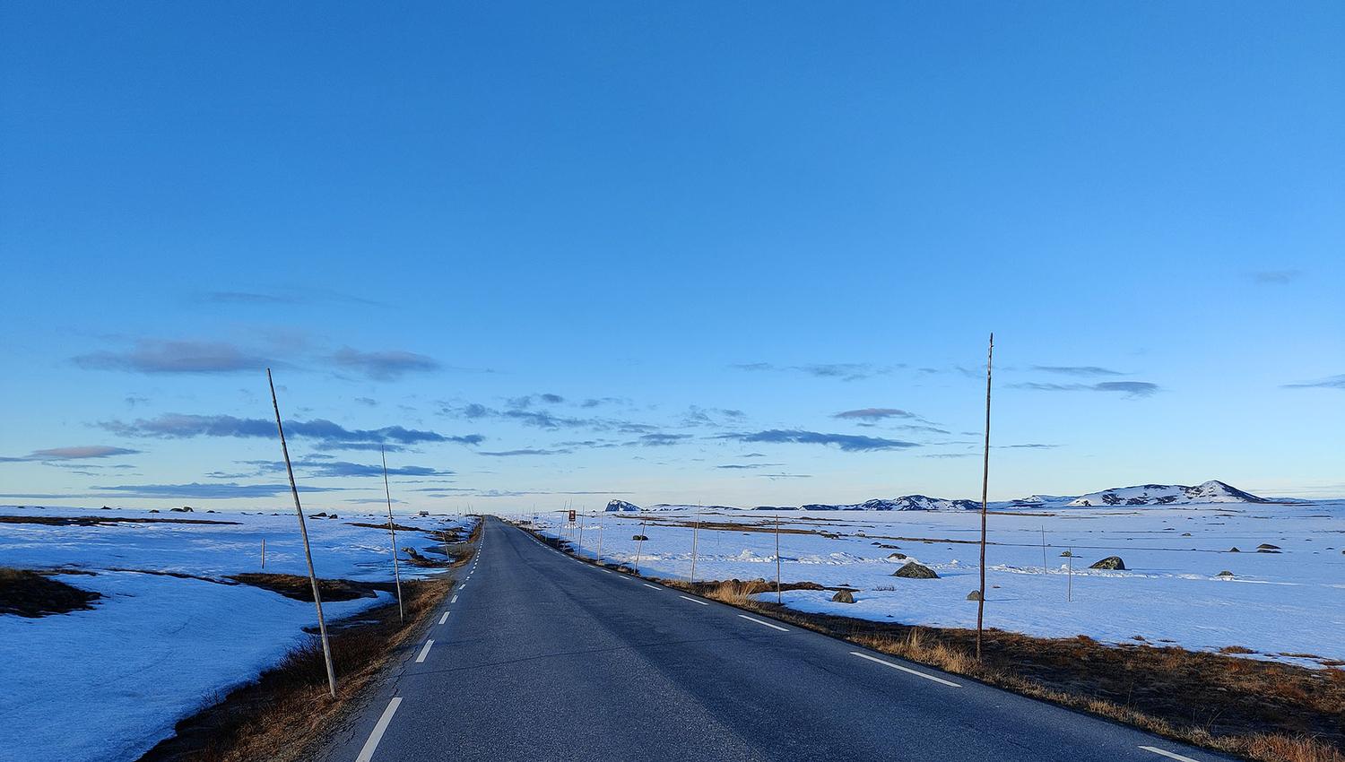 vei over snødekt fjellplatå i blåtimen