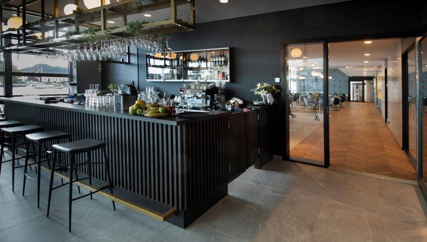 Svart bar med svarte barstoler på Mandal Hotel