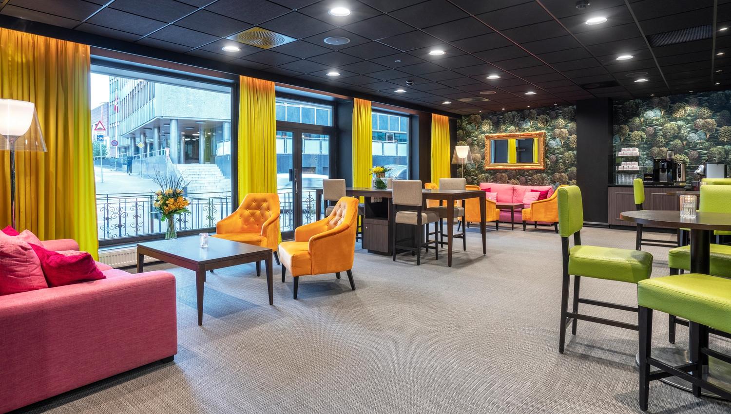 Lobby med sofaer og stoler i rødt, oransj og grønt. Thon Hotel Slottsparken, Oslo. Foto