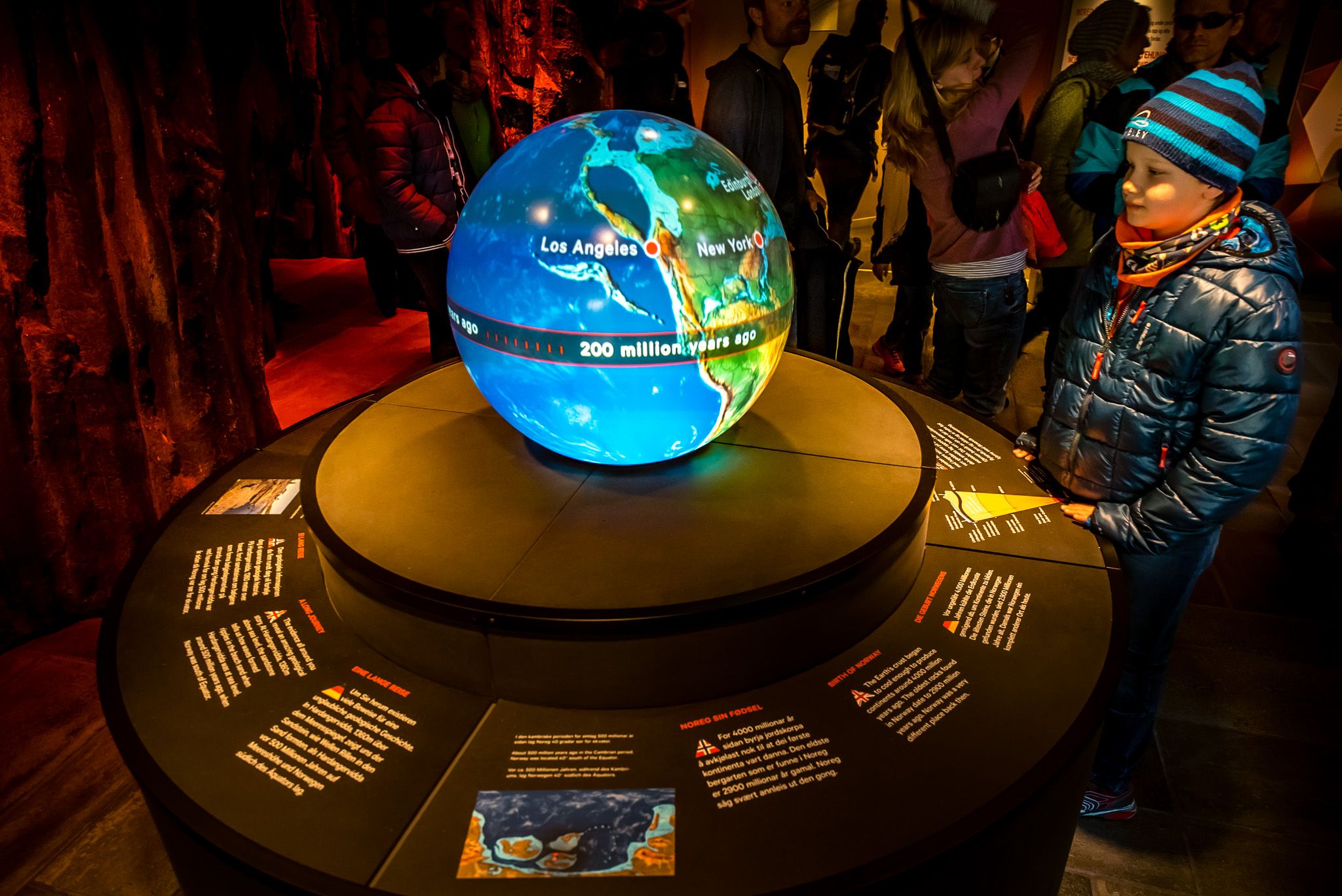 A boy standing in front of a large globe, part of the exhibit at the nature center.