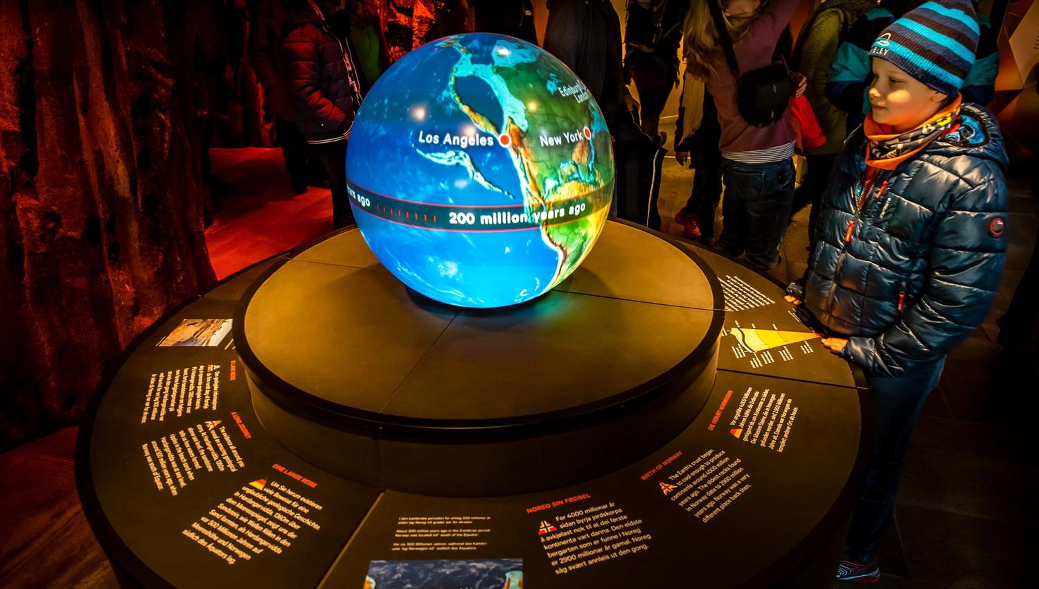 A boy standing in front of a large globe, part of the exhibit at the nature center.