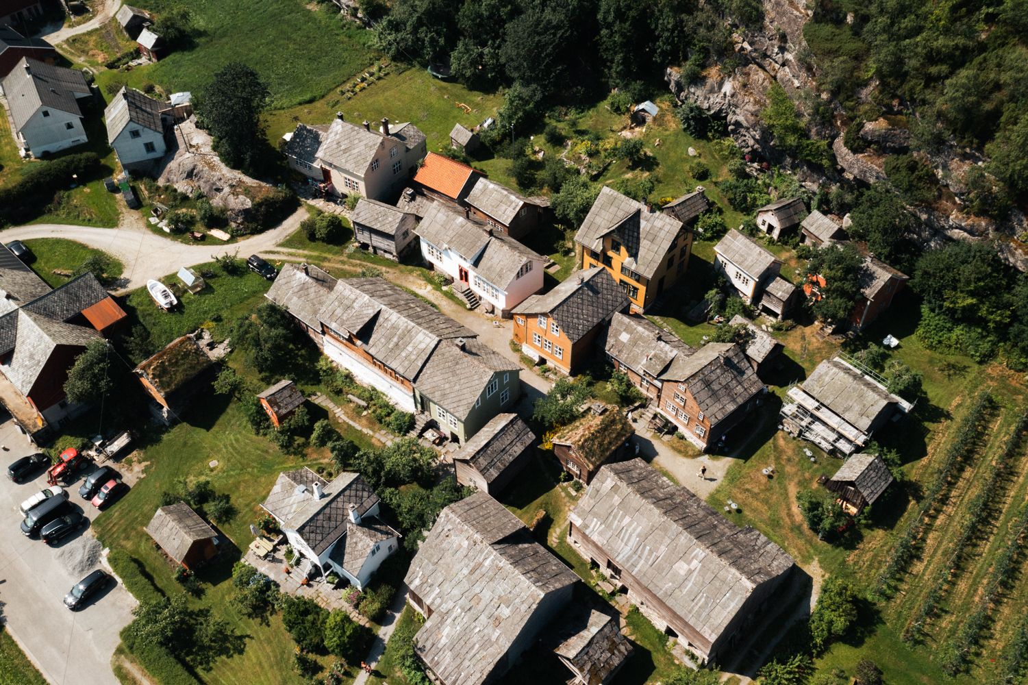 Dronefoto av Agatunet med historiske trehus tett samla, omgitt av grønt landskap og frukthager.