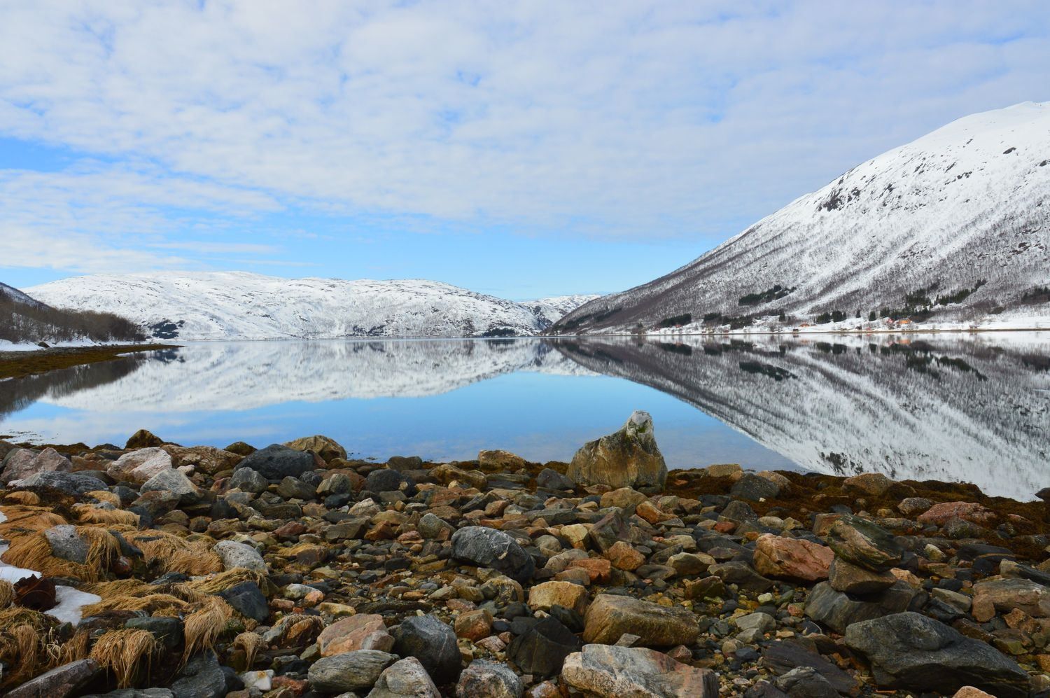 Fjære med klart hav og fjell i bakgrunnen