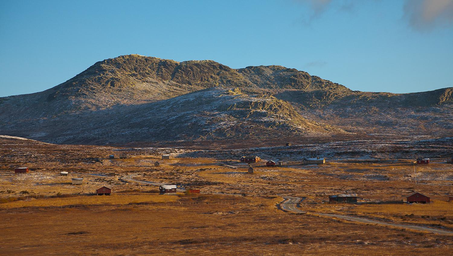 Skaget rises over the summer mountain farming area of Vesleskag. The vegetation is autumn coloured, and the first snow has fallen on the high altitude