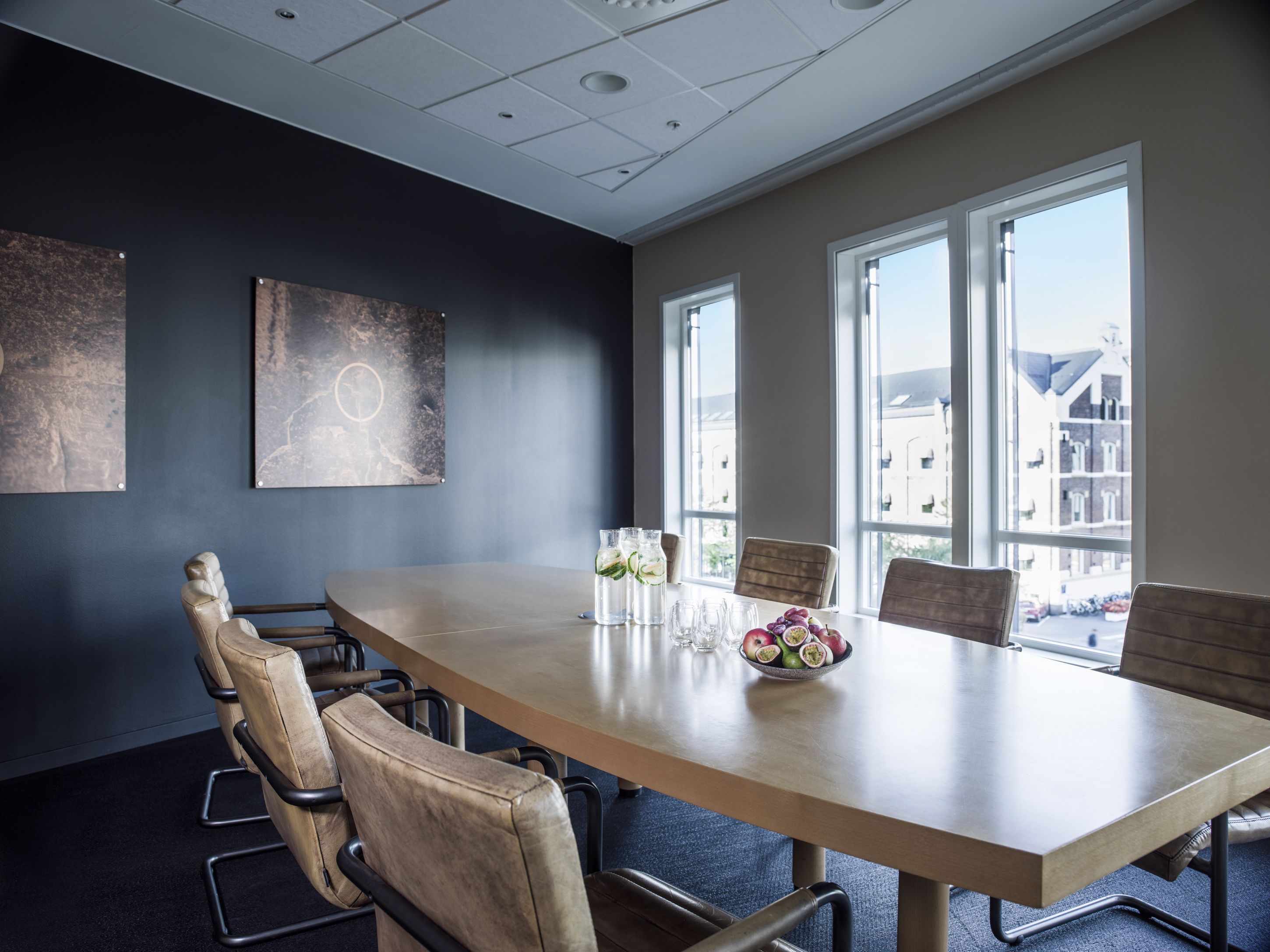 Meeting room with six chairs around the table. Apples and water pitchers on the table. Photo